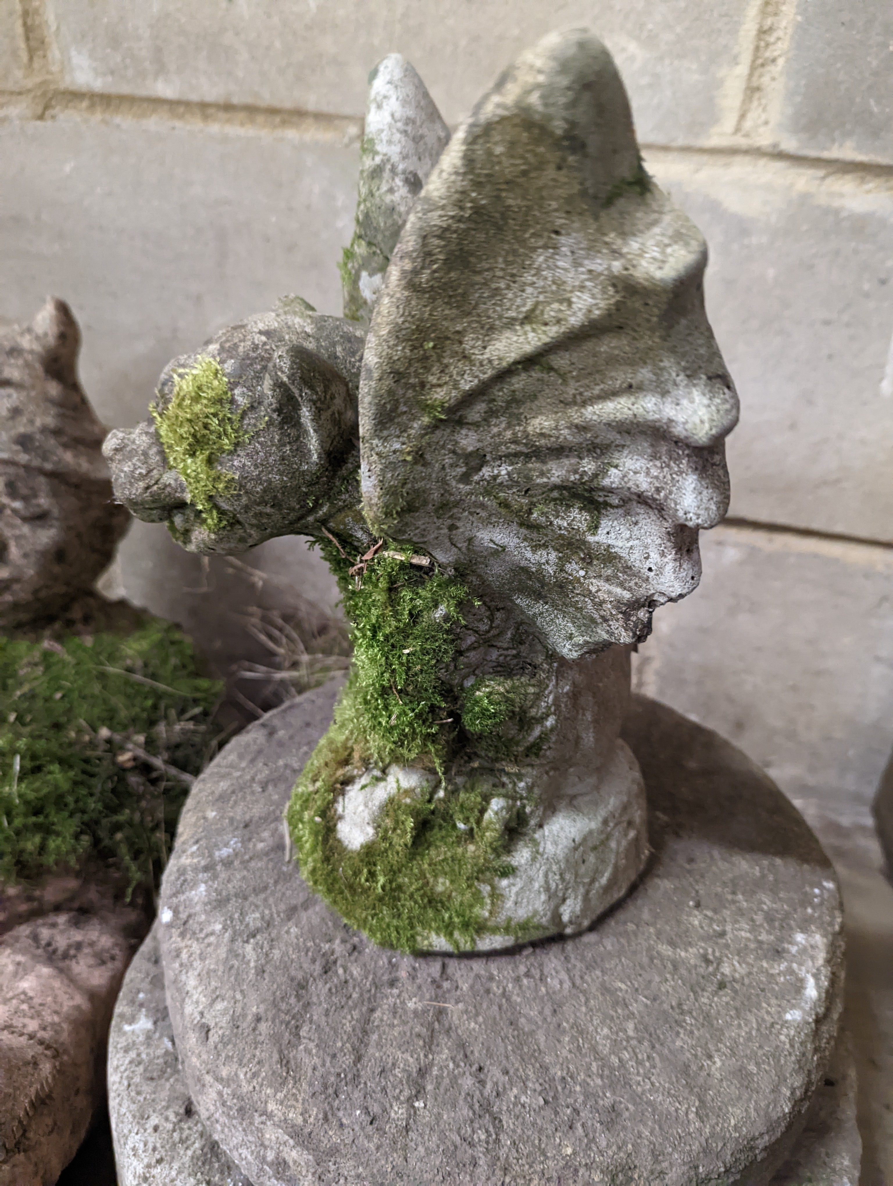 Two small circular mill stones, a reconstituted stone gargoyle and a terracotta reclining pixie garden ornament